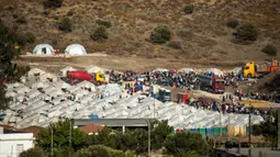 Migran berkumpul di kamp tenda sementara yang baru di Kara Tepe, Lesbos, Yunani, Kamis (17/9/2020). Lebih dari 5.000 pencari suaka yang kehilangan tempat tinggal setelah kebakaran kamp migran terbesar di Yunani, Kamp Moria, kini telah ditempatkan di fasilitas baru. (AP Photo/Panagiotis Balaskas)