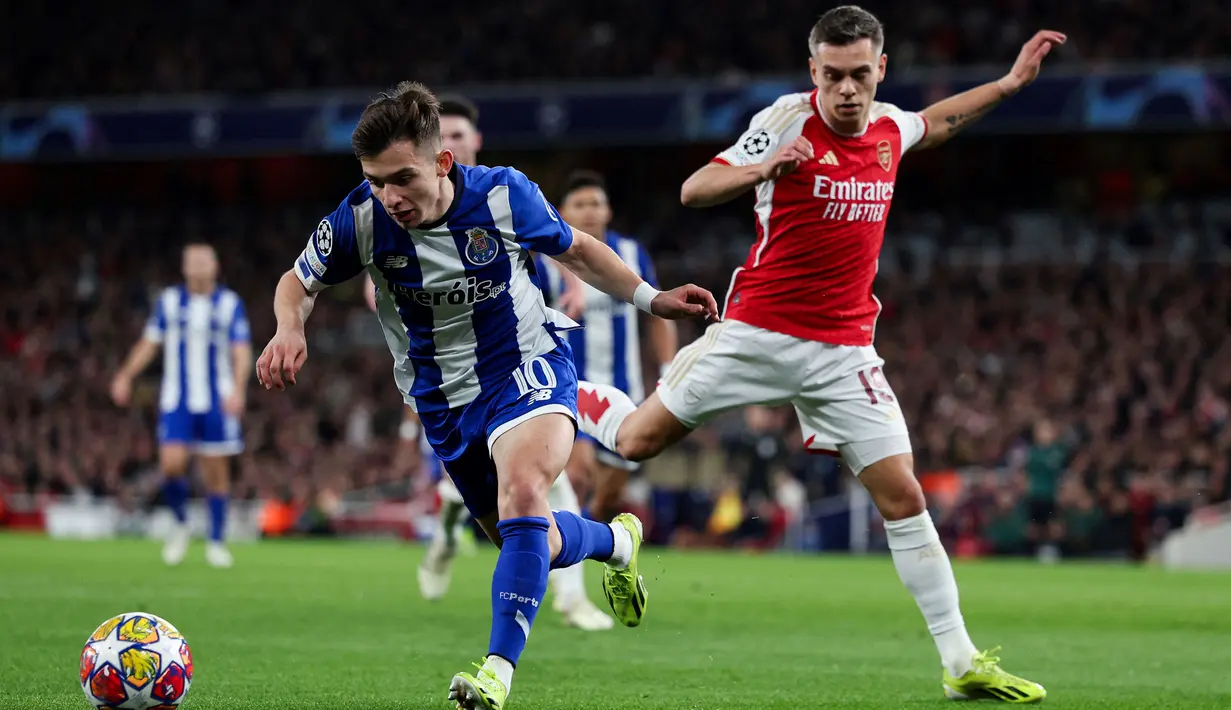 Pemain Arsenal, Leandro Trossard (kanan) berebut bola dengan pemain Porto, Francisco Conceicao pada laga leg kedua 16 besar Liga Champions 2023/2024 di Emirates Stadium, London, Inggris, Rabu (13/03/2024) dini hari WIB. (AFP/Adrian Dennis)