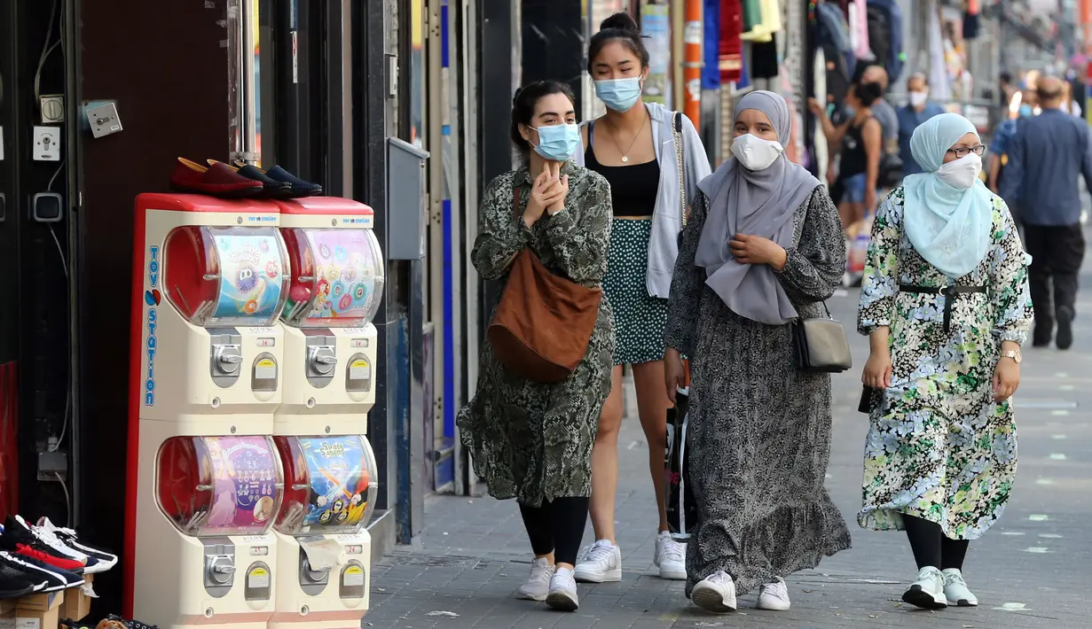 Para perempuan memakai masker di jalanan Brussel, Belgia, Rabu (12/8/2020). Penggunaan masker menjadi wajib di tempat umum di Brussel karena kasus Covid-19 naik ke tingkat kewaspadaan yang menempatkan kota itu di antara yang paling parah terkena dampak corona di Eropa. (François WALSCHAERTS/AFP)