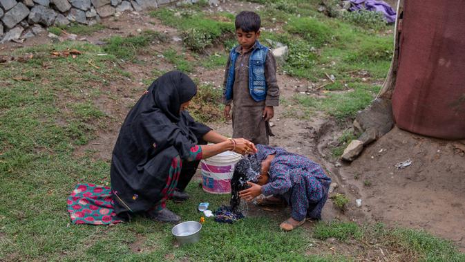 Khalida, perempuan pengembara Kashmir Bakarwal mencuci rambut putrinya di luar kamp sementara di pinggiran Srinagar, India, 31 Agustus 2020. Suku Bakarwals adalah kaum penggembala nomaden di Jammu Kashmir, yang berpindah-pindah mencari padang rumput yang baik untuk ternak mereka. (AP Photo/Dar Yasin