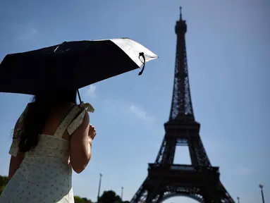 Seseorang berlindung di bawah payung saat berjalan menuju Menara Eiffel di Paris ketika gelombang panas yang memecahkan rekor melanda sebagian besar Eropa Barat pada Kamis 28 Mei 2026. (SIMON WOHLFAHRT/AFP)