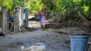 Ratusan rumah terendam, puluhan rusak berat, ribuan warga mengungsi, dan akses jalan utama masih terputus di sejumlah titik. Tampak dalam foto, seorang warga membawa barang-barangnya di jalan yang tertutup lumpur setelah banjir bandang di Meureudu, Kabupaten Pidie Jaya, Provinsi Aceh, pada 29 November 2025. (CHAIDEER MAHYUDDIN/AFP)