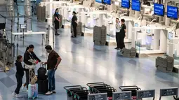 Penumpang menunggu di dekat konter check-in yang kosong di Terminal Internasional Bandara Haneda setelah penerbangan dibatalkan atau ditunda karena badai tropis Jangmi di Tokyo, Jepang, Rabu 3 Juni 2026. (Andrew CAALLERO-REYNOLDS/AFP)