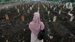 Keluarga berdoa depan pusara makam korban Covid-19 di TPU Srengseng Sawah 2, Jakarta Selatan, Jumat (19/3/2021). Seminggu terakhir intensitas pemakaman korban Covid-19 menurun drastis sebesar rata-rata 20 jenazah/minggu dibandingkan sebelumnya rata-rata 35 jenazah/minggu. (merdeka.com/Arie Basuki)