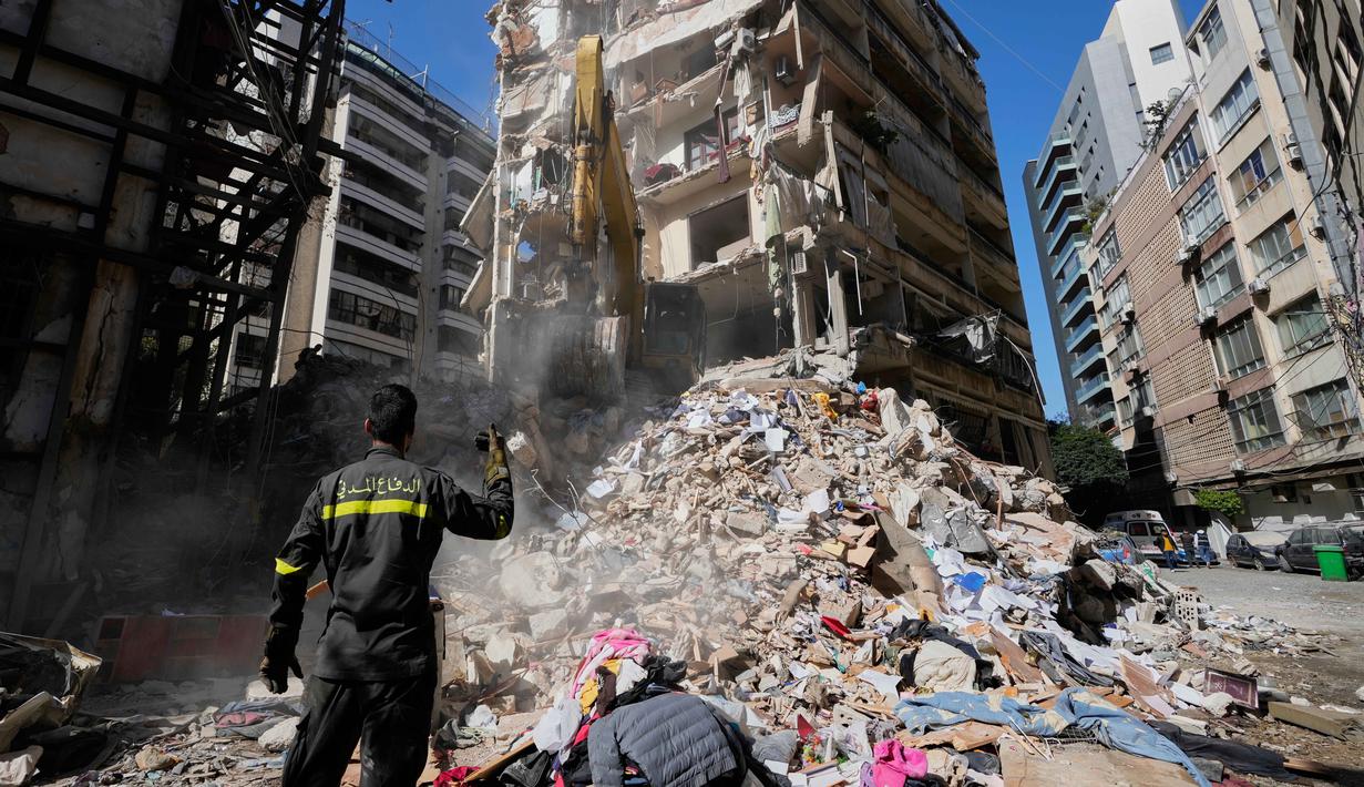 Pada Rabu (8/4/2026), serangan Israel di Lebanon menewaskan ratusan orang dan memicu ancaman balasan dari Iran. Tampak dalam foto, seorang petugas pertahanan sipil Lebanon memberi isyarat ke sebuah ekskavator saat mereka mencari korban di reruntuhan di lokasi bangunan yang hancur akibat serangan udara Israel sehari sebelumnya di pusat kota Beirut, Lebanon, Kamis 9 April 2026. (AP Photo/Hussein Malla)