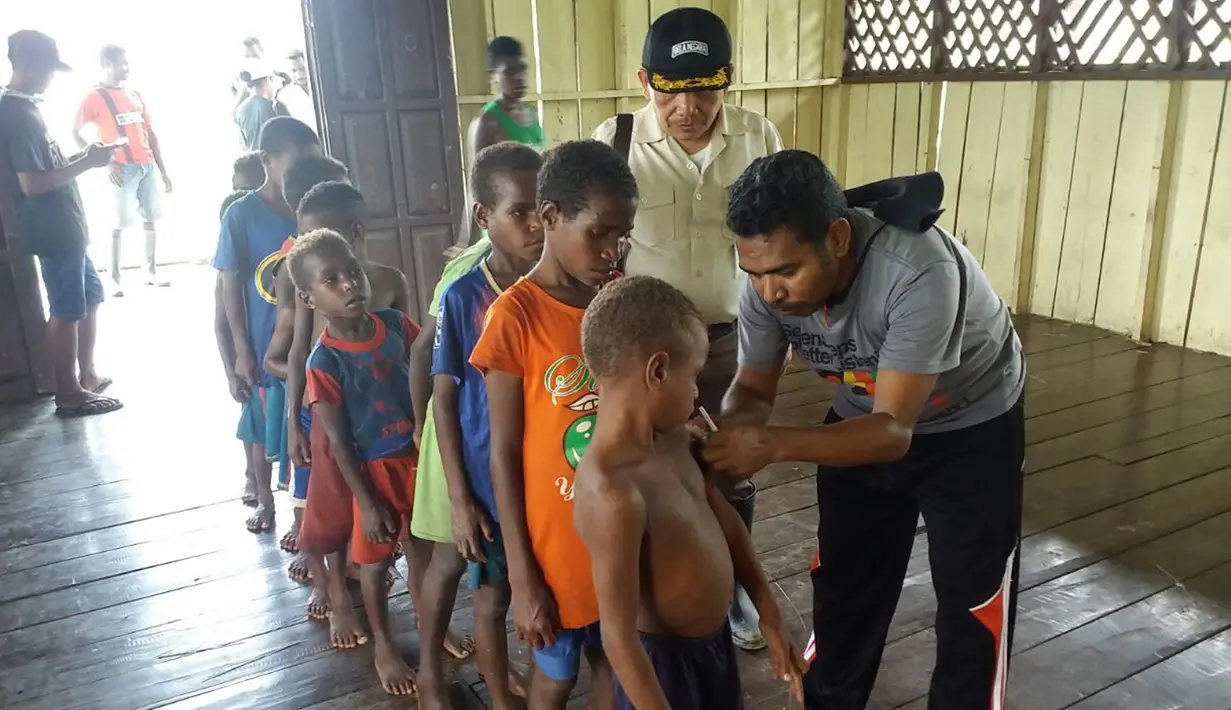 Satgas Kesehatan TNI memberi vaksin campak terhadap anak-anak di Kabupaten Asmat, Papua, Jumat (19/1). Tim Gabungan Satgas Kesehatan TNI KLB menyalurkan bantuan berupa vaksin ke kampung-kampung terpencil di Kabupaten Asmat. (LIputan6.com/Pool/Puspen TNI)