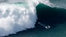 Peselancar unjuk kebolehan saat menaklukkan ombak besar di Praia do Norte atau Pantai Utara, Nazare, Portugal, Rabu (20/11/2019). Ombak di perairan ini disebut-sebut paling menantang dan paling berbahaya di dunia. (AP Photo/Armando Franca)