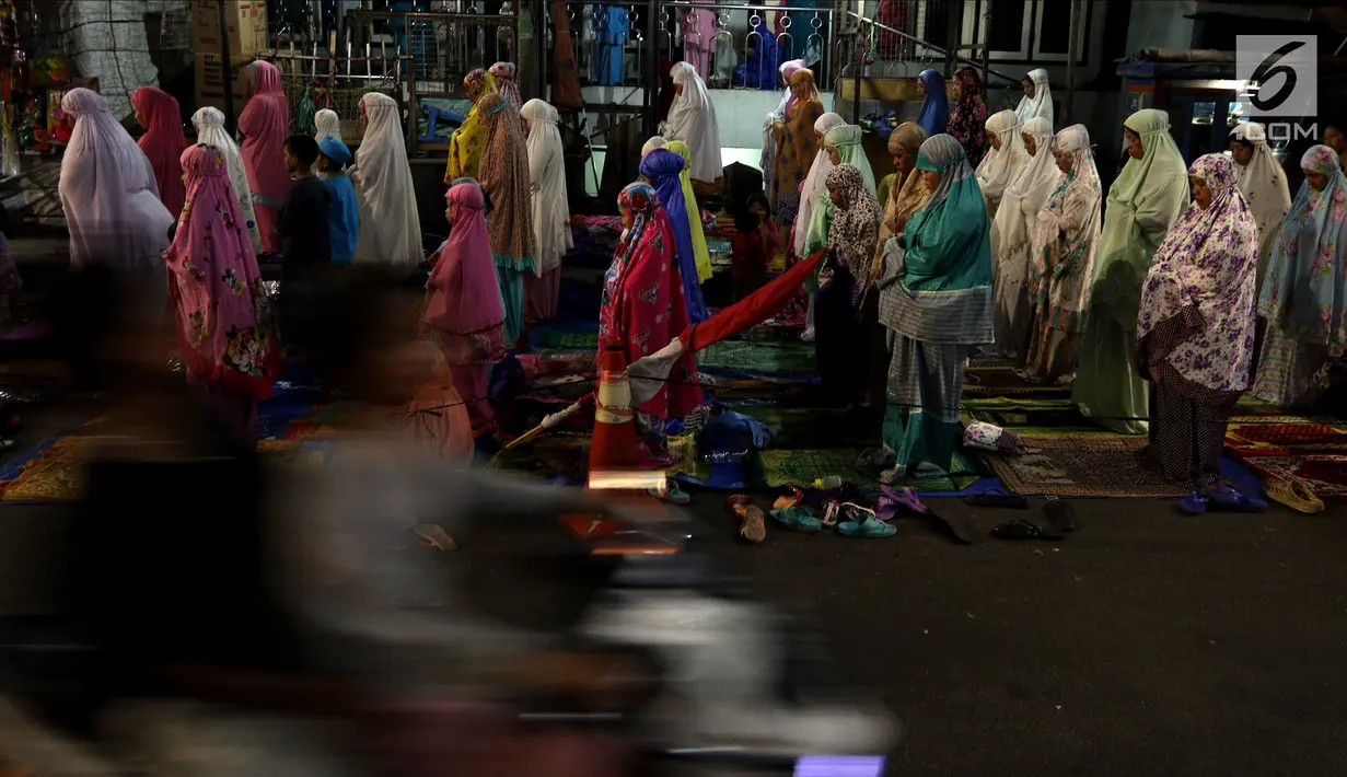 Jemaah melaksanakan salat tarawih hingga ke badan jalan akibat melubernya Musala Miftahul Jannah di Kawasan Pasar Gembrong, Jakarta, Kamis (17/5). (Liputan6.com/JohanTallo)