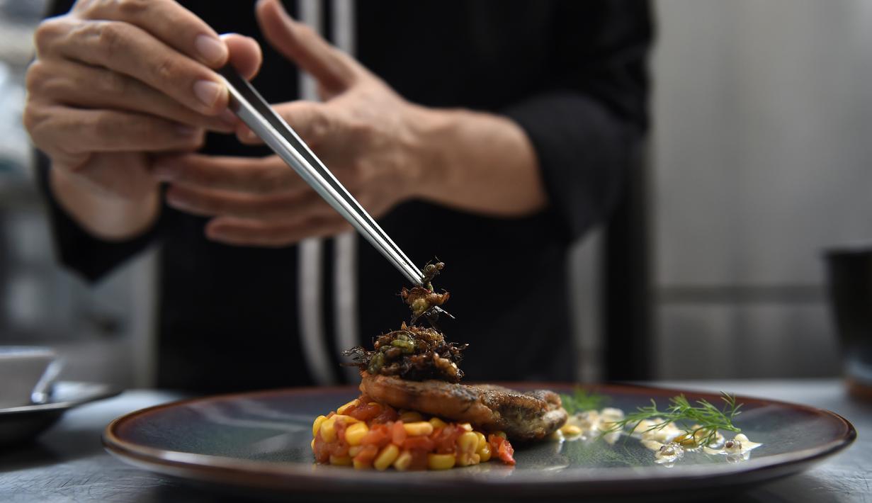 <p>Semut bersayap dihidangkan di atas hidangan fillet ikan di dapur restoran Insects in the Backyard, Bangkok, 15 Agustus 2017. Restoran kelas atas ini menjadi yang pertama membuka menu hidangan makanan dengan kombinasi serangga. (LILLIAN SUWANRUMPHA/AFP)</p>