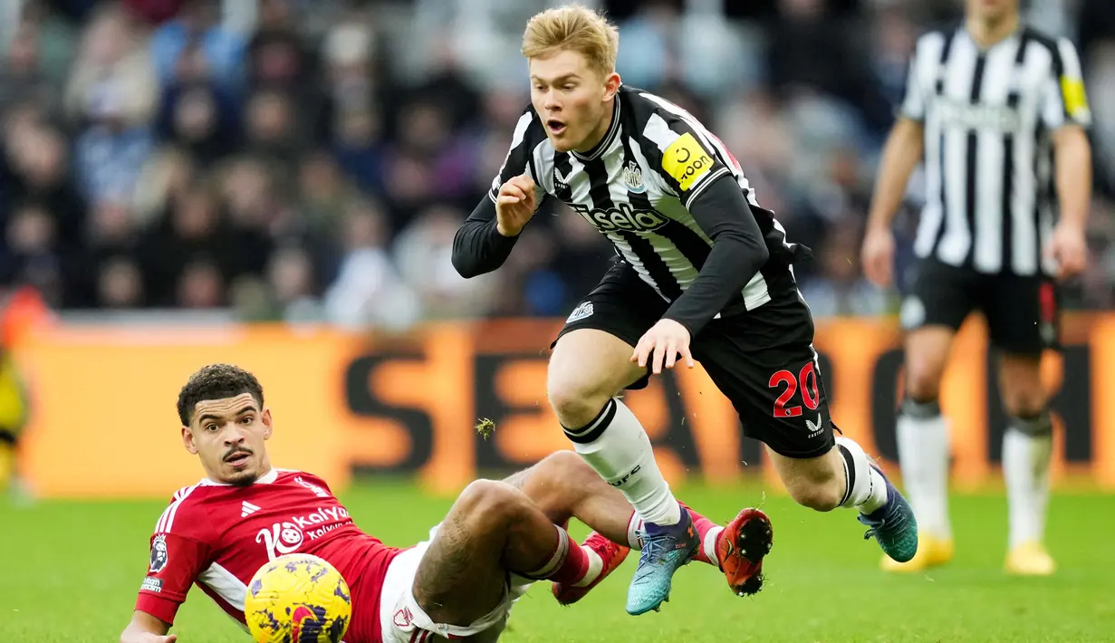 Pemain Newcastle United, Lewis Hall, terjatuh saat berebut bola dengan pemain Nottingham Forest, Morgan Gibbs-White, dalam lanjutan Liga Inggris di St James Park, Selasa (26/12/2023). (AFP/Andu Buchanan)