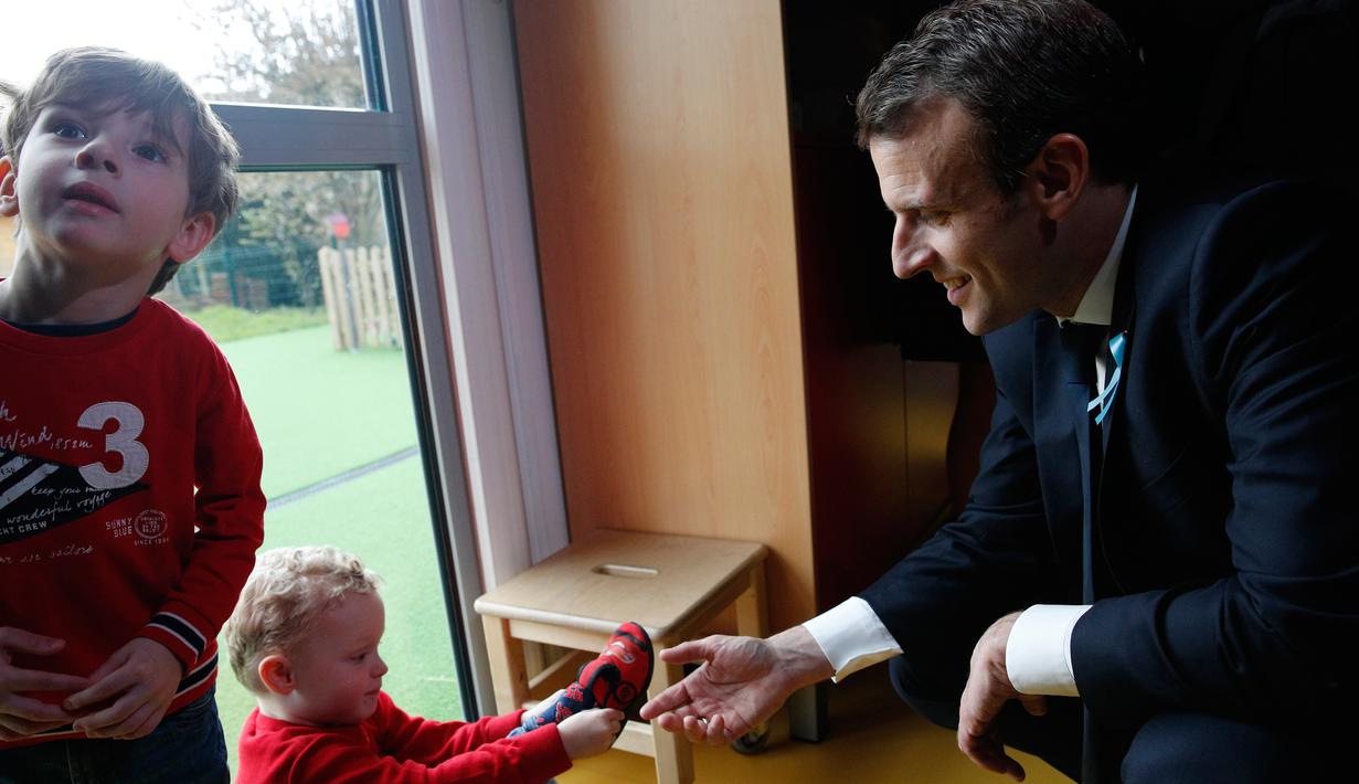Presiden Prancis Emmanuel Macron bermain dengan anak-anak saat mengunjungi Graffiti's- Association Le Moulin Vert di Normandia, Prancis (5/4). Pada kunjungannya Presiden Emmanuel Macron berinteraksi dengan anak-anak autis. (AP / Christophe Ena, Pool)