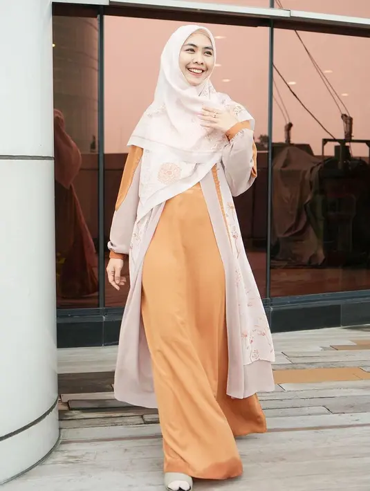 Tampil cerah di hari raya bisa mengenakan dress orange dengan aksen outer yang serasi dengan kerudungnya seperti yang dikenakan Oki Setiana Dewi. [@okisetianadewi]