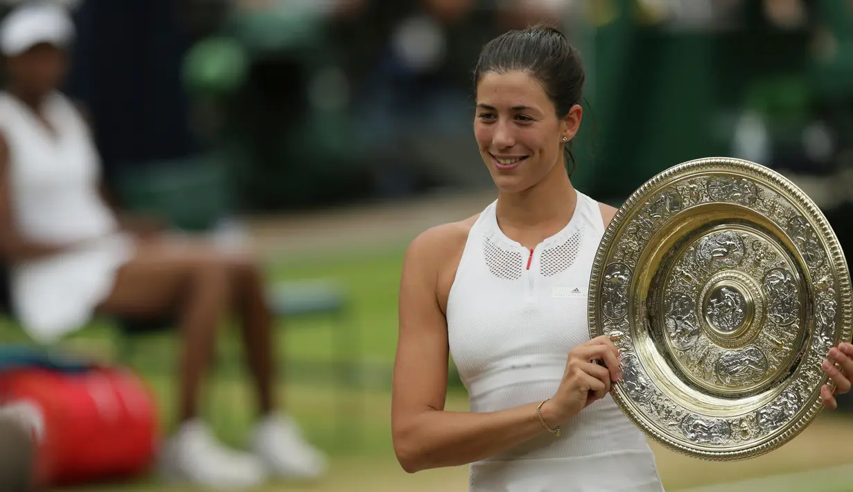 Petenis Spanyol, Garbine Muguruza berpose memegang trofi mengalahkan petenis AS Venus Williams pada final turnamen grand slam Wimbledon 2017 di London, Sabtu (15/7). Muguruza menang dua set langsung 7-5 6-0 atas Venus. (AP Photo/Tim Ireland)