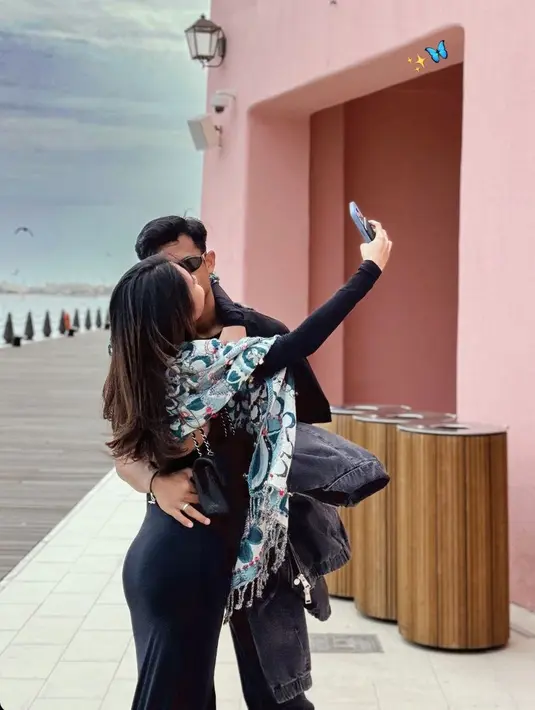 <p>Dicium mesra sang suami, Azizah tampil dengan dress bodycon model backless warna hitam. Dipadukan pashmina bercorak warna hijau, lengkap dengan tas Chanel warna serasi. [@azizahsalsha_]</p>