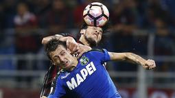 Bek AC Milan, Gustavo Gomez berebut bola dengan bek Sassuolo, Francesco Acerbi pada lanjutan liga Italia di San Siro, Milan (3/9). AC Milan menang dramatis atas Sassuolo dengan skor 4-3. (AFP Photo/Marco Bertorello)