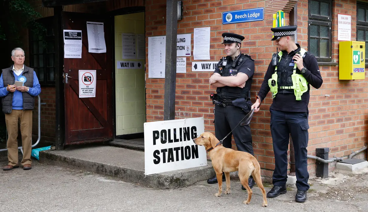Anggota kepolisian bersama seekor anjing berjaga di TPS Kota Maidenhead, Kamis (8/6). Pemilu Inggris dimulai dengan penjagaan ketat menyusul dua serangan teror yang merenggut 30 jiwa dalam waktu kurang dua pekan. (AP Photo/Alastair Grant)