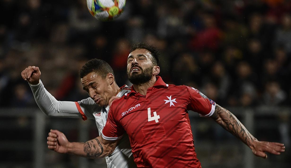 Duel udara dilakukan Steve Borg dan penyerang Spanyol. Rodrigo pada laga kedua Kualifikasi Piala Eropa 2020 yang berlangsung di Stadion Ta Qali, Malta, Rabu (27/3). Spanyol menang 2-0 atas Malta. (AFP/Filippo Monteforte)
