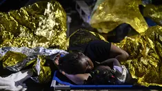 Seorang perempuan dan seorang anak tidur di luar pusat penerimaan migran Lampedusa, Sisilia, Kamis pagi, 14 September 2023. (AP Photo/Valeria Ferraro)