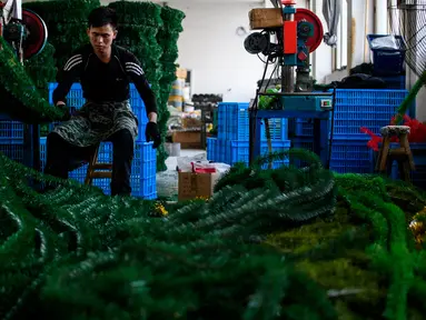 Seorang pekerja menyelesaikan pembuatan pohon Natal di pabrik Sun Xudan, Yiwu, China (7/12). Sun Xudan adalah pabrik terbesar di China yang memproduksi berbagai aksesoris Natal, termasuk pohon cemara buatan. (AFP Photo/Johannes Eisele)