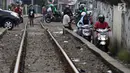 Pengendara melintas di samping rel kereta yang berada di kawasan Banjir Kanal Barat, Jakarta, Selasa (20/3). Selain mempersingkat waktu, pengendara beralasan hal itu demi memperpendek jarak tempuh. (Liputan6.com/Arya Manggala)