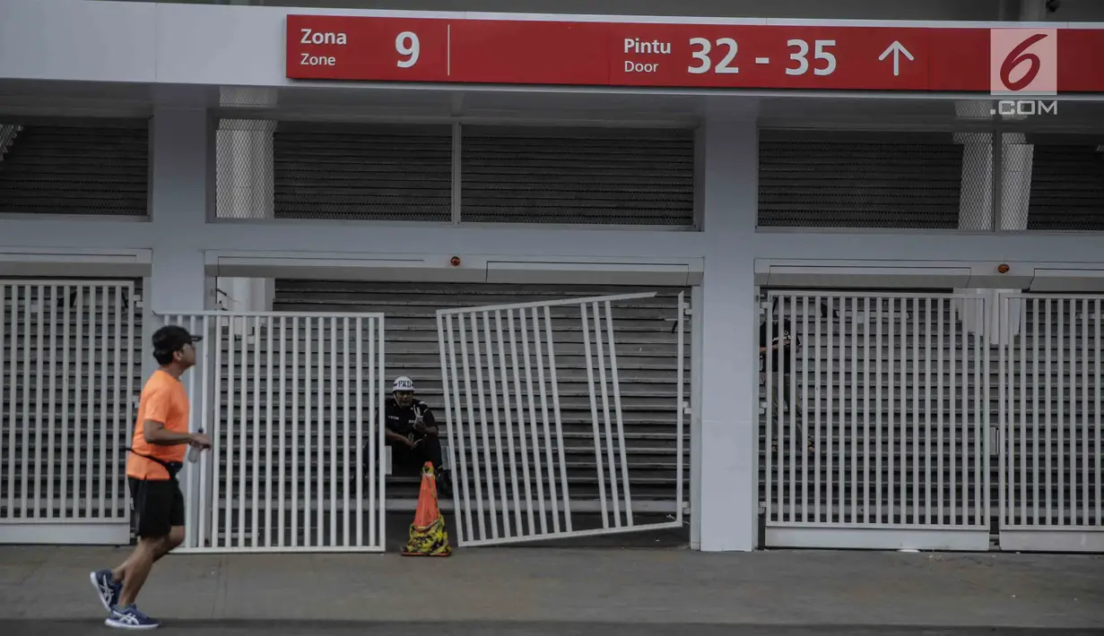 Warga berolahraga melintasi pintu masuk zona 9 Stadion Utama Gelora Bung Karno yang rusak pada Final Piala Presiden 2018, Jakarta, Minggu (18/2). Kerusakan disebabkan suporter salah satu tim sepakbola yang merangsek masuk. (Liputan6.com/Faizal Fanani)