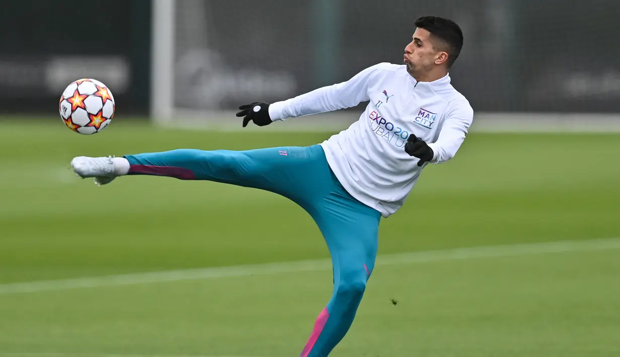 Bek Manchester City, Joao Cancelo menendang bola saat mengikuti sesi latihan di tempat latihan Manchester City di Manchester, barat laut Inggris (4/4/2022). Man City akan bertanding melawan Atletico Madrid pada leg pertama perempat final Liga Champions di Etihad Stadium. (AFP/Paul Ellis)