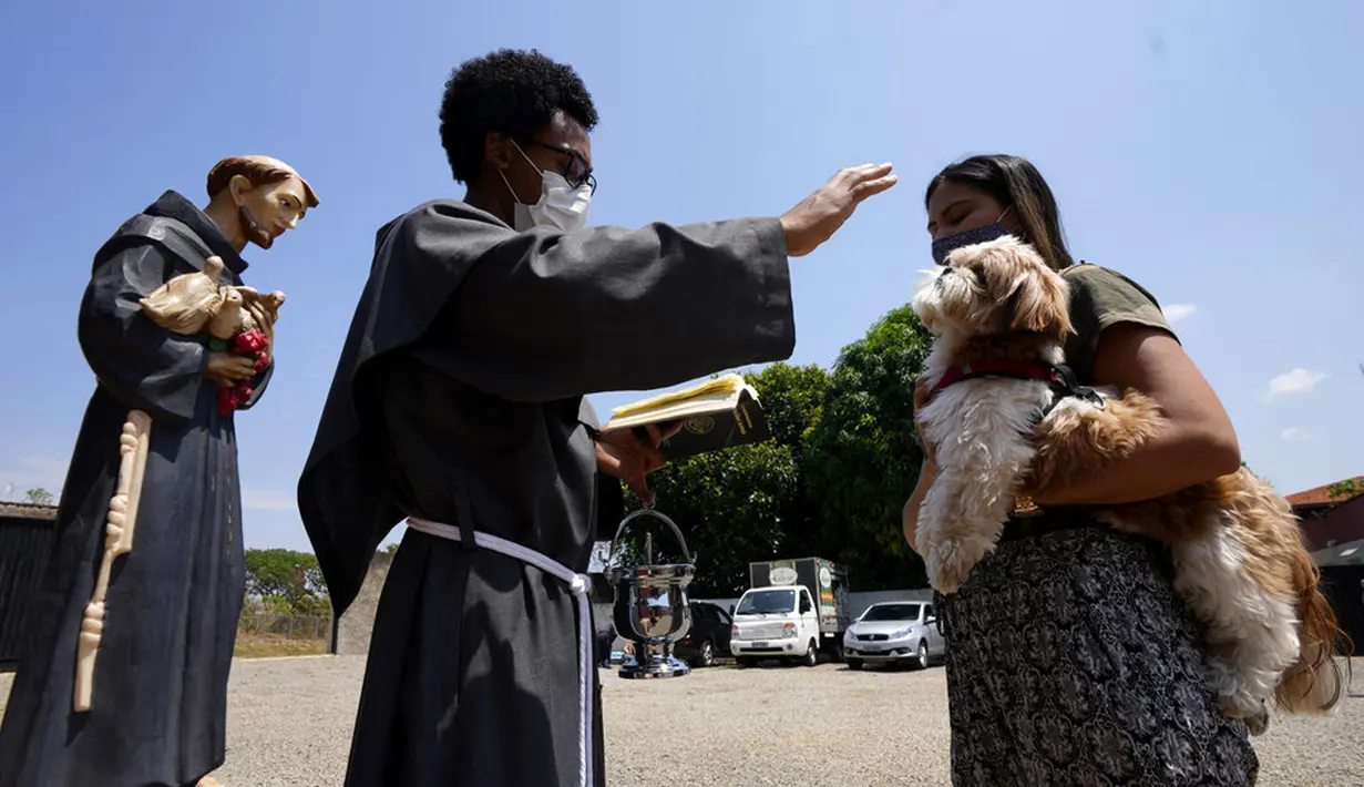 Seorang Fransiskan memberkati seekor anjing peliharaan dalam misa untuk menghormati Santo Fransiskus dari Assisi pada Hari Raya Santo di Brasilia, Brasil, Senin (4/10/2021). Santo Katolik dianggap sebagai pelindung hewan. (AP Photo/Eraldo Peres)