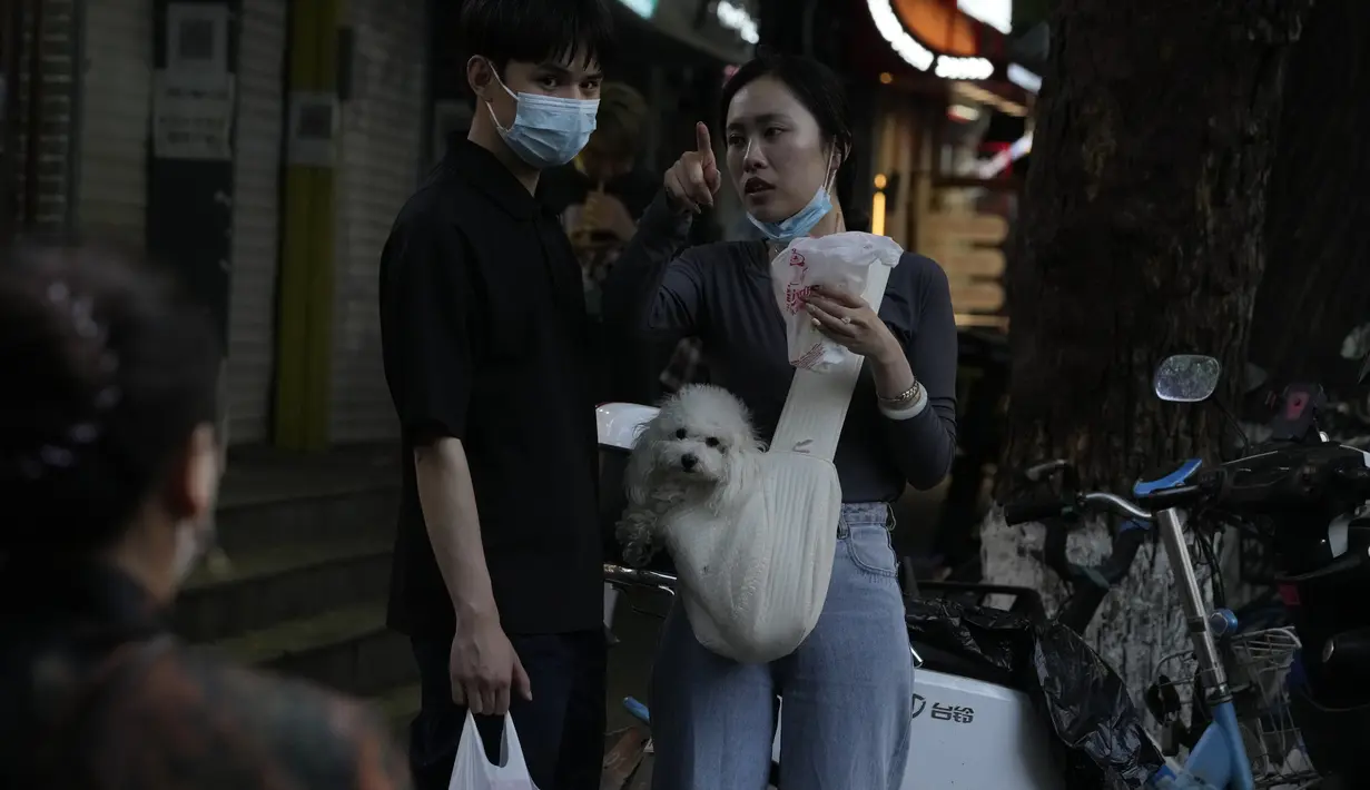 Warga mengobrol saat mengunjungi jalan ritel yang sepi di Beijing (24/5/2022). Beijing memperpanjang perintah bagi pekerja dan pelajar untuk tinggal di rumah dan memerintahkan pengujian massal tambahan pada Senin ketika kasus COVID-19 meningkat di ibu kota China. (AP Photo/Ng Han Guan)