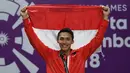 Jonatan Christie tersenyum sambil mengibarkan bendera Merah Putih saat upacara penghargaan cabang olahraga badminton Asian Games 2018, Jakarta, Selasa (28/8). Jonatan menang tiga set langsung 21-18, 20-22, dan 21-15. (AFP Photo/Sonny Tumbelaka)