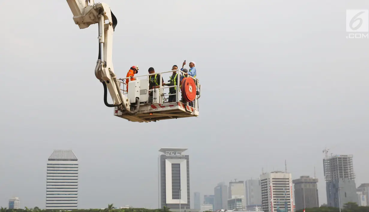 Pengunjung menaiki Bronto Skylift yang disediakan petugas pemadam kebakaran di Monas, Jakarta, Minggu (23/11). Bronto Skylift merupakan fasilitas yang disediakan Pemprov DKI Jakarta untuk melihat Monas dari dekat. (Liputan6.com/JohanTallo)
