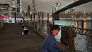 Angga Yunanda asyik duduk di pinggir sungai dengan pemandangan jembatan Queensboro Bridge. (Foto: Instagram/@anggayunandareal16)