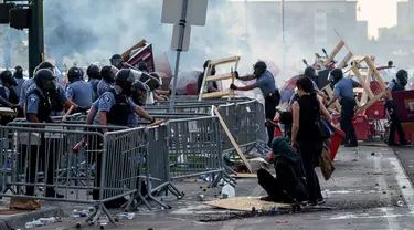 Polisi menyingkirkan barikade yang dibuat demonstran saat unjuk rasa atas kematian George Floyd oleh polisi di luar Third Police Precinct, Minneapolis, Minnesota, Amerika Serikat, Rabu (27/5/2020). Kematian George Floyd memicu kerusuhan di Minneapolis. (Kerem Yucel/AFP)