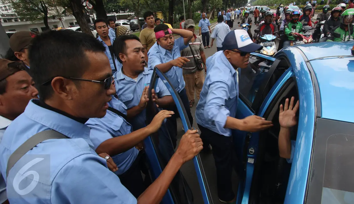 Para sopir taksi memaksa pengemudi taksi yang masih beroperasi untuk bergabung saat aksi sweeping di Jalan Medan Merdeka Selatan, Jakarta, Senin (14/3). Ribuan sopir taksi dan bus kota akan menggelar unjuk rasa di Istana. (Liputan6.com/Immanuel Antonius)