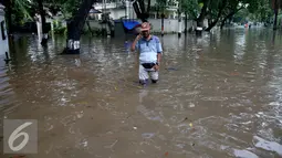 Warga melintasi banjir yang menggenangi Kommplek Perumahan yang Banjir di Hang Lekiu, Kebayoran Baru, Jakarta, Jumat (11/11). Hujan deras yang mengguyur Jakarta sejak siang tadi menyebabkan sejumlah wilayah tergenang banjir. (Liputan6.com/Johan Tallo)