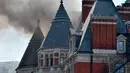 Asap hitam terlihat membubung dari atap Hotel Mandarin Oriental yang mengalami kebakaran di London, Inggris, Rabu (6/6). Menurut pihak pemadam kebakaran hingga saat ini belum diketahui penyebab kebakaran tersebut. (John Stillwell/PA via AP)