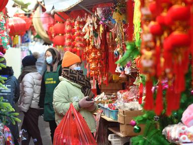 Seorang wanita membeli pernak-pernik dekorasi menjelang Hari Tahun Baru di sebuah pasar di Qingdao, di provinsi Shandong timur China pada 25 Desember 2022. Warga China mulai berburu pernak-pernik Tahun Baru seperti lampion, kartu tahun baru, baju, dan hiasan rumah. (AFP/STR)