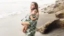Liburan ke pantai, Yasmine kompak bersama si buah hati memakai baju kembar. Gadis mungil ini tampak nyaman berada di gendongan sang ibu. (Instagram/yaswildblood)
