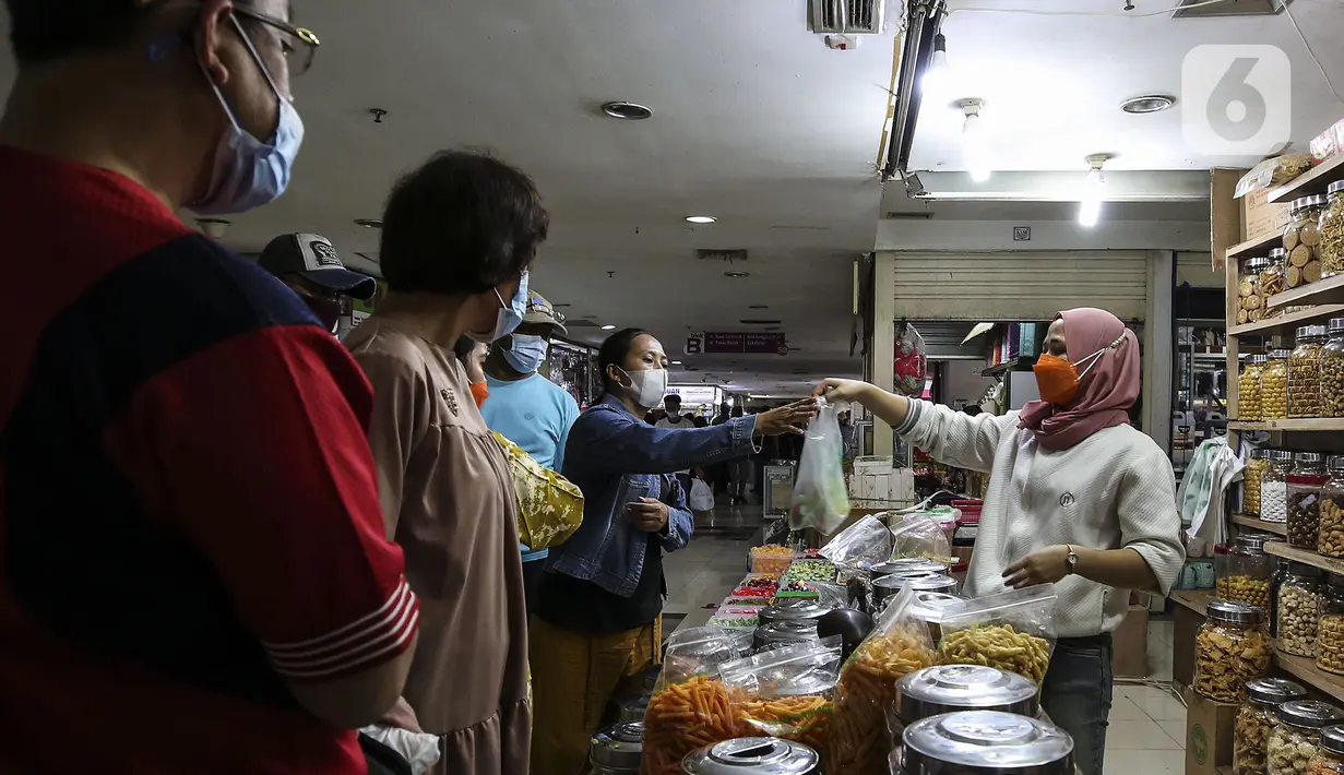 Pedagang kue kering melayani pembeli di Pasar Mayestik, Jakarta, Senin (3/5/2021). Omzet penjualan kue kering menjelang Lebaran tahun ini mengalami peningkatan hingga 70 persen dari tahun sebelumnya yang mengalami penurunan hingga 70 persen. (Liputan6.com/Johan Tallo)