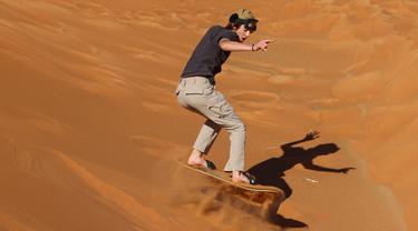 Turis bermain sandboarding (papan seluncur) di gurun Dubai pada 11 Januari 2021. Di sini para wisatawan dapat mencoba sensasi bermain sandboarding sambil memandang hamparan lautan pasir cokelat. (Photo by GIUSEPPE CACACE / AFP)