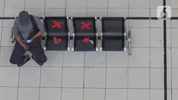 Calon penumpang melihat ponsel sambil menanti waktu keberangkatan bus Antar Kota Antar Provinsi di Terminal Bus Terpadu Pulo Gebang, Jakarta, Kamis (31/12/2020). Memasuki libur pergantian tahun sejumlah calon penumpang terus berdatangan di Terminal Bus Terpadu Pulo Gebang. (Liputan6.com/Helmi Fithri