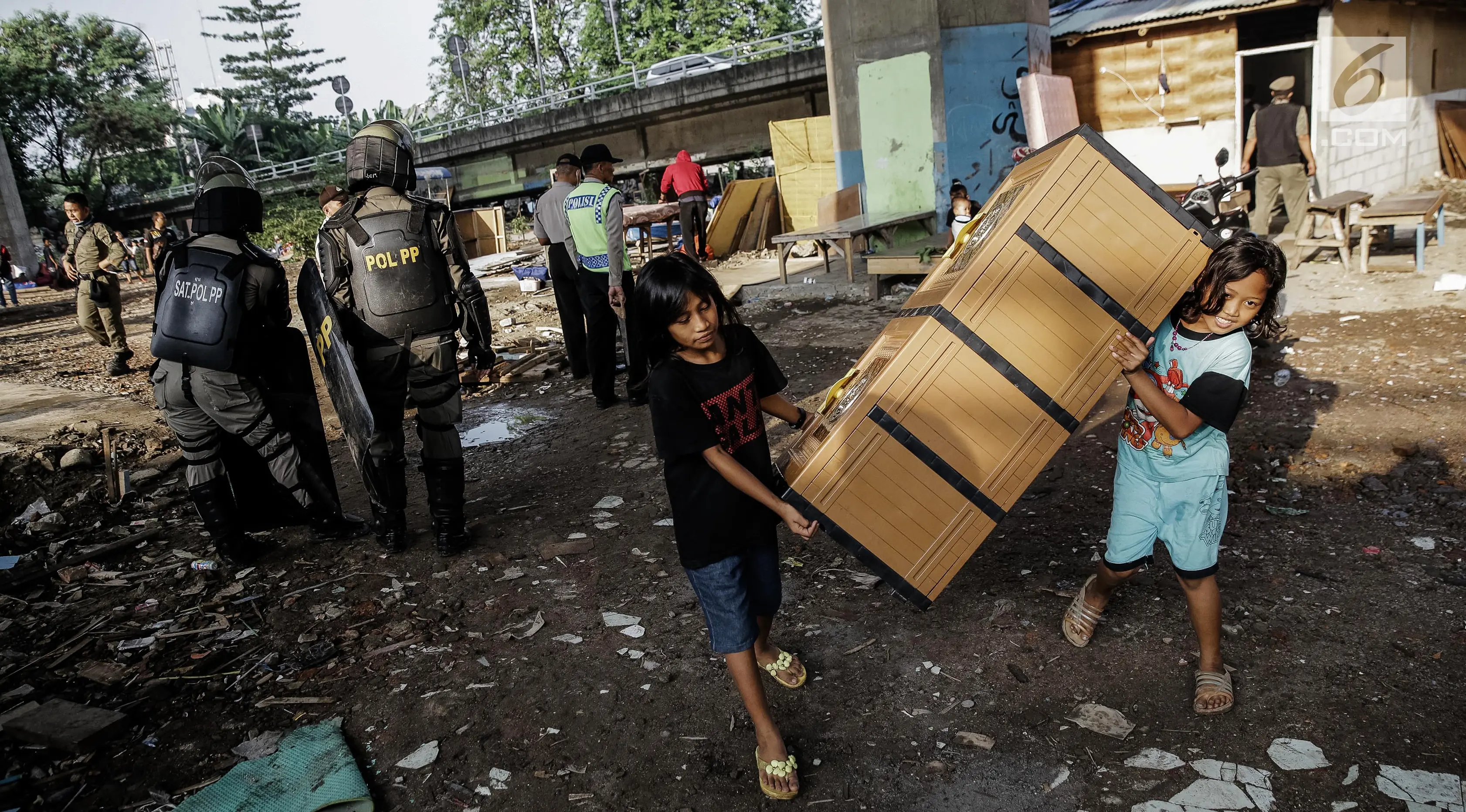 Dua orang anak menyelamatkan barangnya saat penertiban di bawah kolong Tol Teluk Intan, Jakarta, Rabu (14/6). Gubernur DKI Jakarta Djarot Saiful Hidayat menegaskan, kawasan tersebut dilarang digunakan sebagai tempat pemukiman. (Liputan6.com/Faizal Fanani)