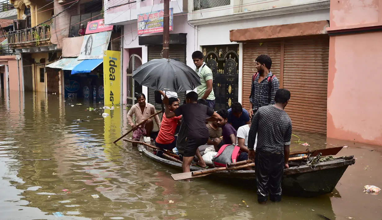Warga menaiki perahu saat melintasi jalan yang terendam banjir di Chhota Baghara, Allahabad, India, Rabu (11/8/2021). Hujan lebat menyebabkan banjir di Allahabad. (SANJAY KANOJIA/AFP)