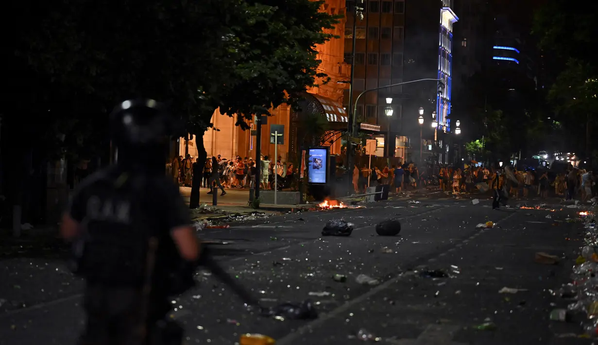 Polisi anti huru hara bentrok dengan suporter setelah perayaan  timnas Argentina meraih juara Piala Dunia Qatar 2022 di lingkungan Obelisk di Buenos Aires (20/12/2022). Jutaan orang kecewa ketika parade bus yang membawa pemain Argentina harus meninggalkan lokasi itu yang menimbulkan gesekan antara supporter dengan petugas keamanan. (AFP/Luis Robayo)