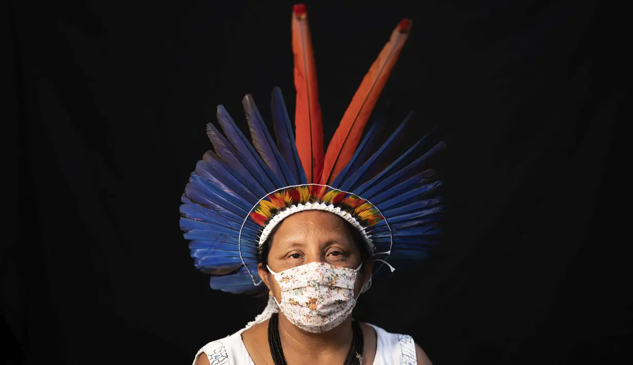 Sonia Vilacio (46) dari kelompok etnis pribumi Sateré Mawé mengenakan pakaian tradisional sukunya dan masker saat pandemi virus corona COVID-19 di Manaus, Brasil, Rabu (27/5/2020). Sonia Vilacio pernah jatuh sakit dengan tanda-tanda terpapar COVID-19. (AP Photo/Felipe Dana)