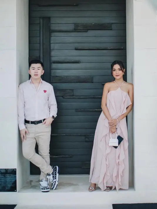 Andi tampil elegan dengan dress panjang high neck. Dress pink tersebut dilengkapi renda. Ia membawa mini bag putih.  (@andiannsyah)