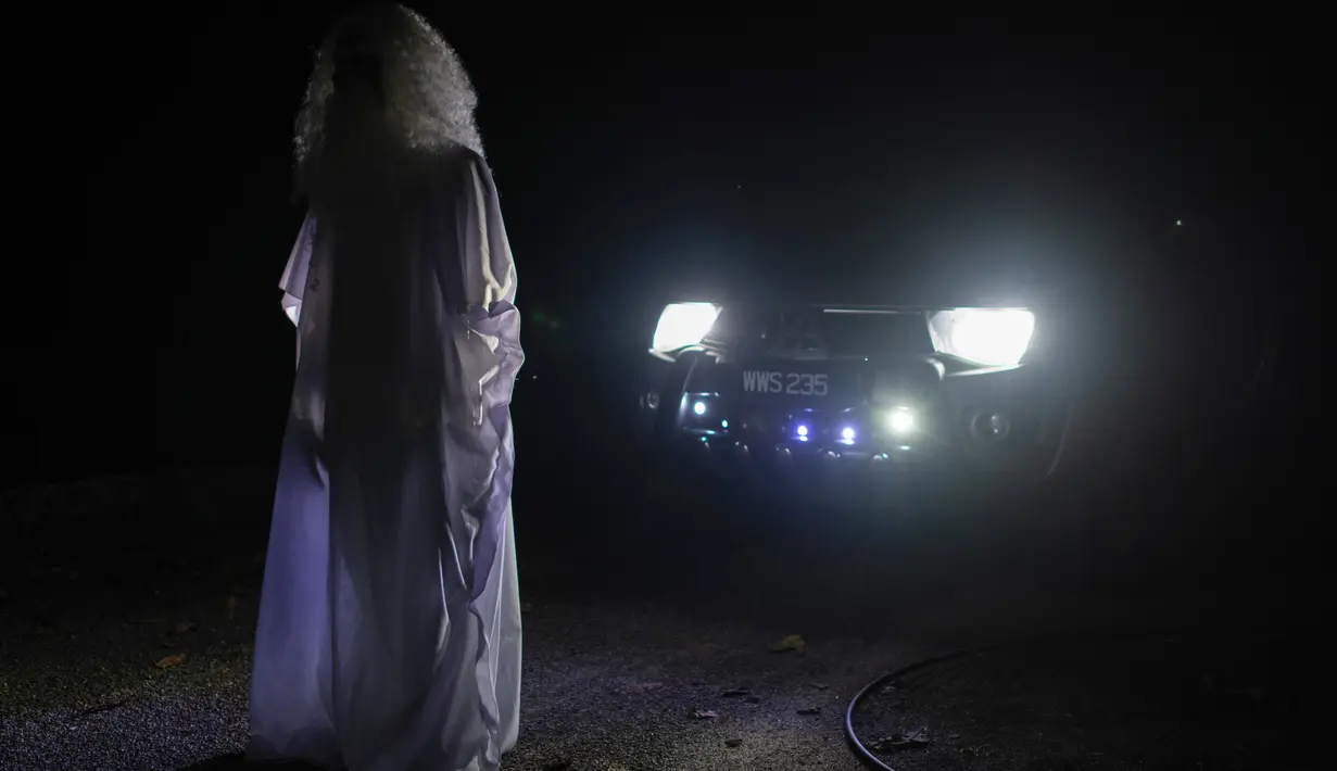 Urabil Alias, 38, mengenakan kostum hantu berdiri di depan mobil sekitar perumahan selama aturan pembatasan gerakan atau Movement Control Order di Terengganu, Malaysia, 16 April 2020. Aksi pria itu untuk menakuti warga agar tidak keluar rumah selama lockdown akibat virus corona. (Mohd RASFAN/AFP)