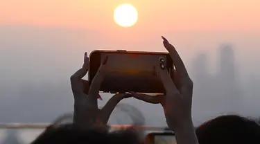 Orang-orang mengambil gambar matahari terbenam terakhir tahun ini di dek observasi menara Namsan di Seoul, Korea Selatan, Minggu (31/12/2023). (Jung Yeon-je / AFP)