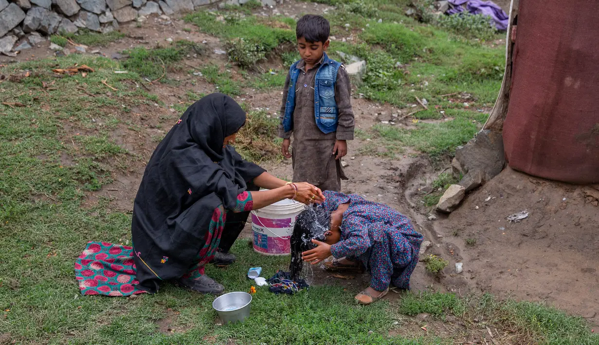 Khalida, perempuan pengembara Kashmir Bakarwal mencuci rambut putrinya di luar kamp sementara di pinggiran Srinagar, India, 31 Agustus 2020. Suku Bakarwals adalah kaum penggembala nomaden di Jammu Kashmir, yang berpindah-pindah mencari padang rumput yang baik untuk ternak mereka. (AP Photo/Dar Yasin