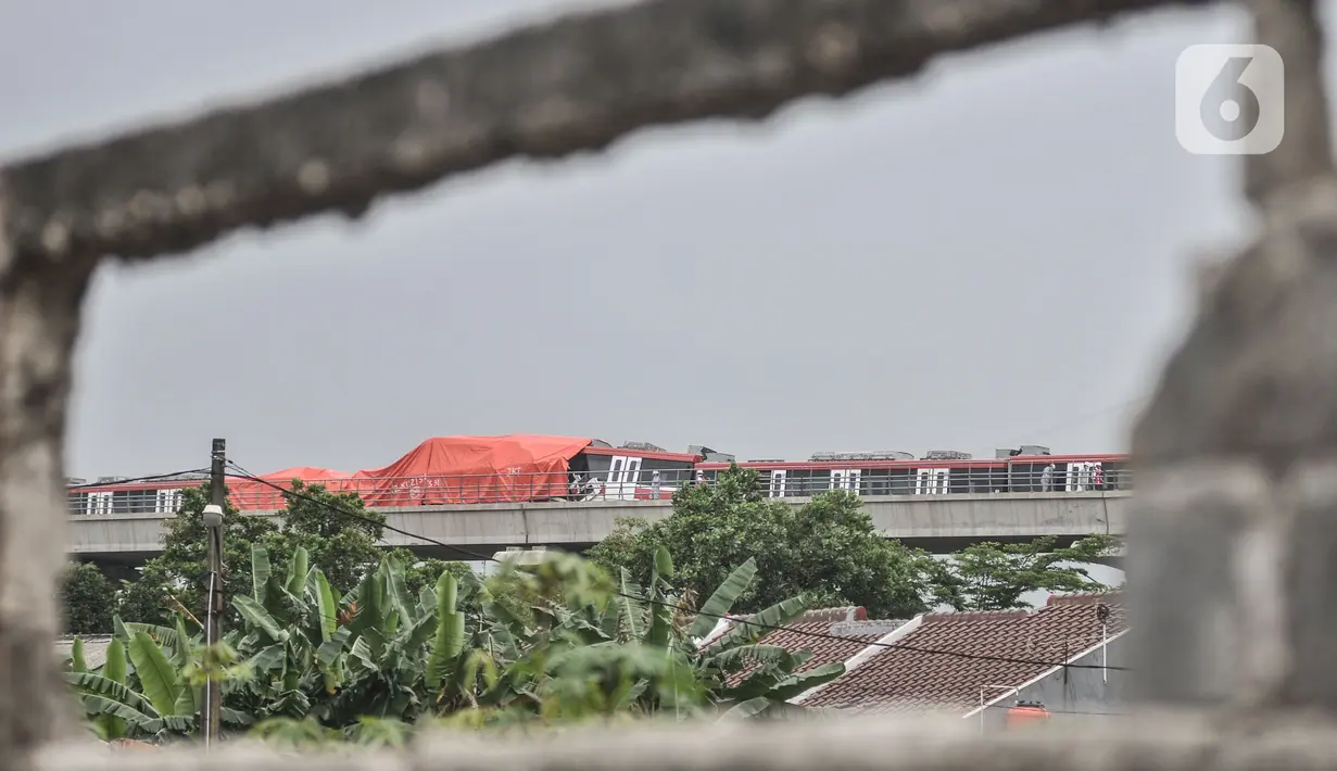 Petugas menggunakan terpal oranye untuk menutupi kereta LRT Jabodebek usai kecelakaan di kawasan Munjul, Cibubur, Jakarta, Senin (25/10/2021). Belum diketahui penyebab tabrakan tersebut dan hingga kini petugas masih menjaga di area kecelakaan. (merdeka.com/Iqbal S Nugroho)