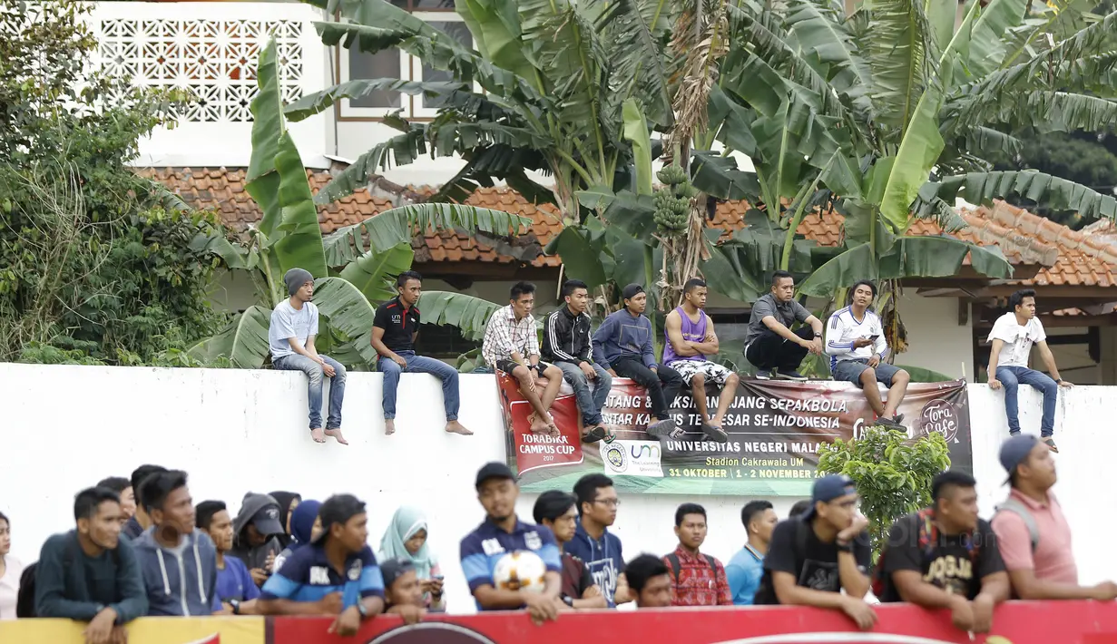 Suporter menonton laga antara Universitas Muhammadiyah Malang (UMM) melawan Universitas Negeri Malang (UM) pada laga final Torabika Campus Cup 2017 di Stadion UM, Malang, Kamis, (02/11/2017). UMM menang 2-0 atas UM. (Bola.com/M Iqbal Ichsan)